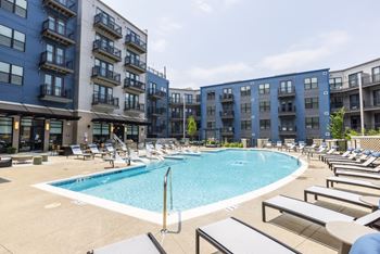 A swimming pool with chaise lounge chairs and a building in the background